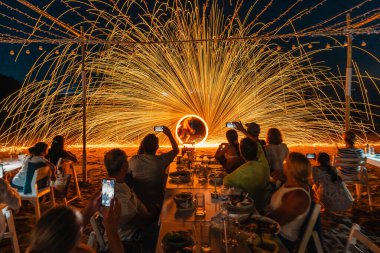 Koh Samet, Rayong, Tayland-2025 Aralık 19: Turistler bir gece etkinliği sırasında plajda olağanüstü bir yangın dönüşü performansı izleyip kaydettiler.