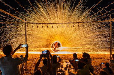 Koh Samet, Rayong, Tayland-2025 Aralık 19: Turistler bir gece etkinliği sırasında plajda olağanüstü bir yangın dönüşü performansı izleyip kaydettiler.