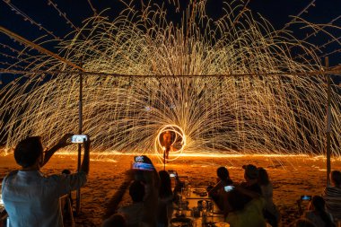 Koh Samet, Rayong, Tayland-2025 Aralık 19: Turistler bir gece etkinliği sırasında plajda olağanüstü bir yangın dönüşü performansı izleyip kaydettiler.
