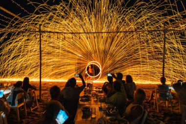Koh Samet, Rayong, Tayland-2025 Aralık 19: Turistler bir gece etkinliği sırasında plajda olağanüstü bir yangın dönüşü performansı izleyip kaydettiler.