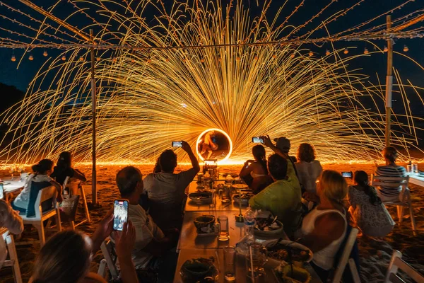 Koh Samet, Rayong, Tayland-2025 Aralık 19: Turistler bir gece etkinliği sırasında plajda olağanüstü bir yangın dönüşü performansı izleyip kaydettiler.