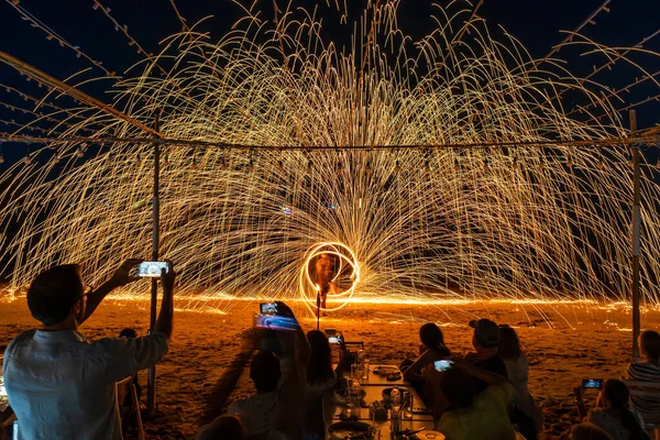 Koh Samet, Rayong, Tayland-2025 Aralık 19: Turistler bir gece etkinliği sırasında plajda olağanüstü bir yangın dönüşü performansı izleyip kaydettiler.