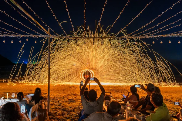 Koh Samet, Rayong, Tayland-2025 Aralık 19: Turistler bir gece etkinliği sırasında plajda olağanüstü bir yangın dönüşü performansı izleyip kaydettiler.