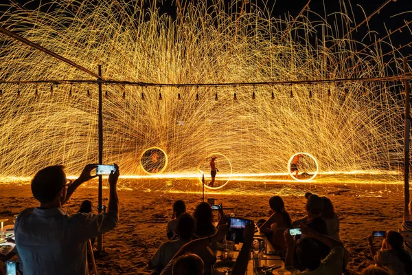 Koh Samet, Rayong, Tayland-2025 Aralık 19: Turistler bir gece etkinliği sırasında plajda olağanüstü bir yangın dönüşü performansı izleyip kaydettiler.
