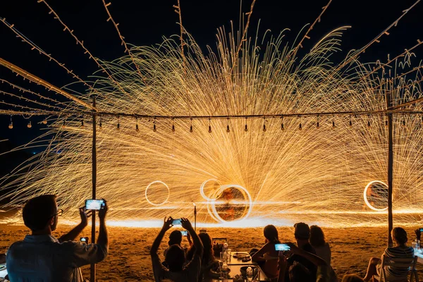 Koh Samet, Rayong, Tayland-2025 Aralık 19: Turistler bir gece etkinliği sırasında plajda olağanüstü bir yangın dönüşü performansı izleyip kaydettiler.