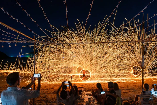 Koh Samet, Rayong, Tayland-2025 Aralık 19: Turistler bir gece etkinliği sırasında plajda olağanüstü bir yangın dönüşü performansı izleyip kaydettiler.
