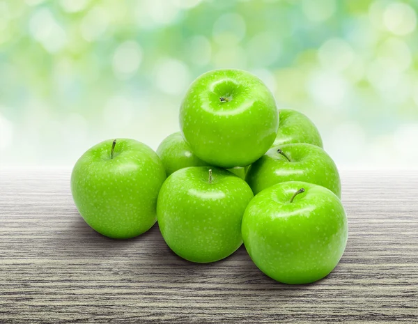 Зеленое яблоко на деревянном столе с природой bokeh фон — стоковое фото