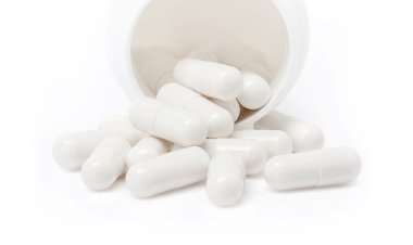 Beyaz arka plan üzerinde izole şişe dökülen beyaz ilaç kapsül