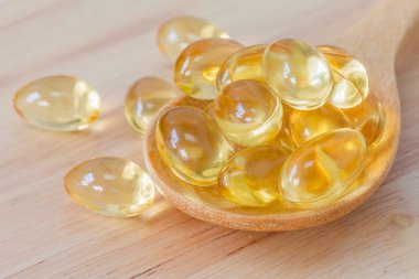 Tahta kaşık ve ahşap arka plan balık yağı takviyesi kapsülünde