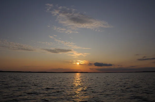 Belo pôr do sol através de pequenas nuvens sobre o lago — Fotografia de Stock