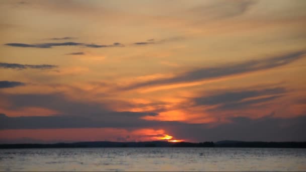 Fargerike skyer under en imponerende solnedgang på en innsjø. – stockvideo