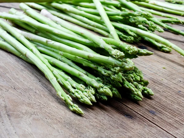 Grüner frischer Spargel auf hölzernem Hintergrund — Stockfoto