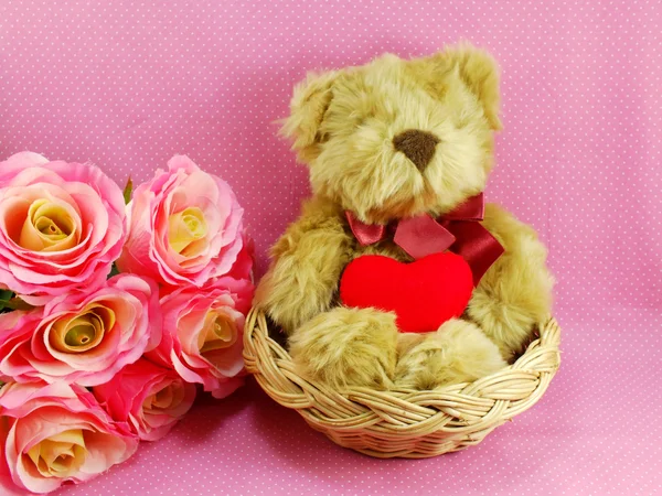 Osito de peluche con corazón rojo en la cesta con fondo rosa — Foto de Stock