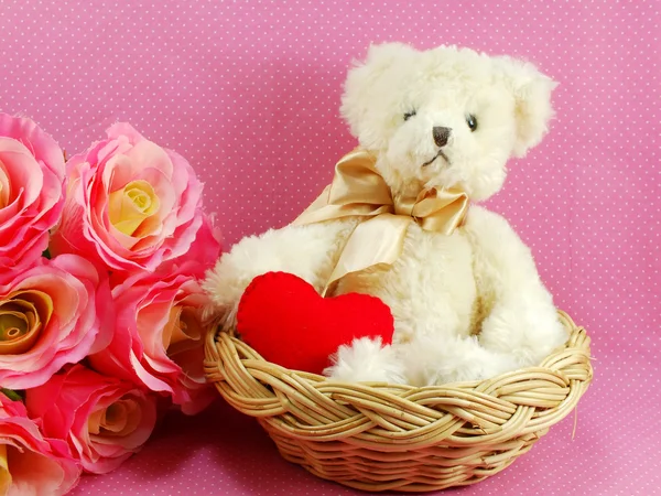 Teddy bear with red heart in the basket with pink background Stock Image