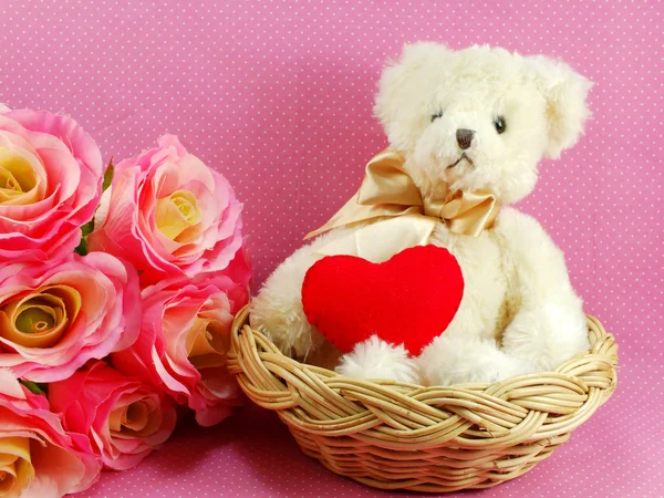 Teddy bear with red heart in the basket with pink background Royalty Free Stock Photos