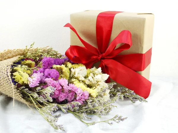 Confezione regalo artigianale in carta con fiocco a nastro e mazzo di fiori con trama in tessuto — Foto Stock