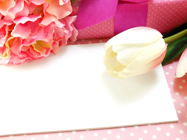 白的礼品卡和郁金香人造花粉红色背景 — 图库照片