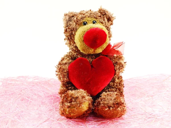 Bonito ursinho de pelúcia com coração vermelho no fundo rosa — Fotografia de Stock