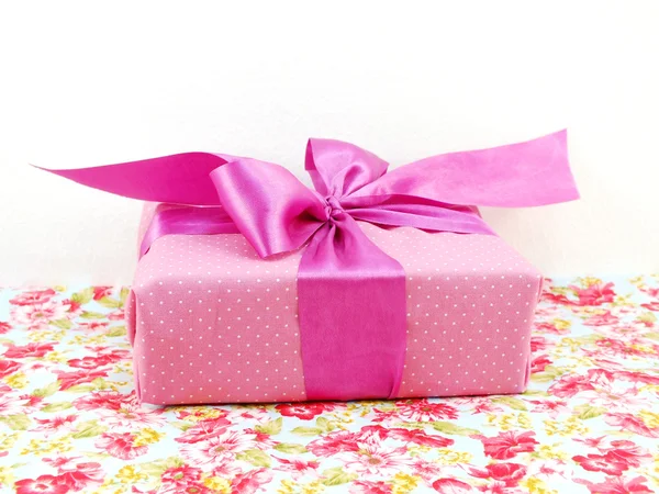 Růžový polka dot gif box s růžovými luk na potištěných tkanin — Stock fotografie