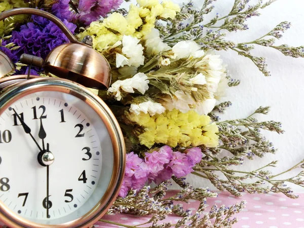 Spring time with alarm clock and artificial flowers bouquet background — Stock Photo, Image