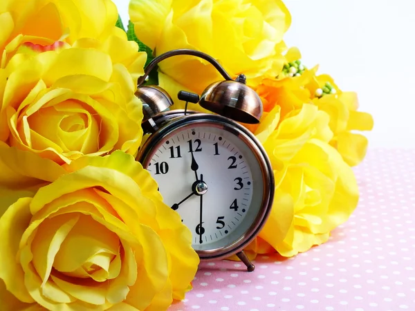 Spring time with alarm clock and artificial flowers bouquet background — Stock Photo, Image
