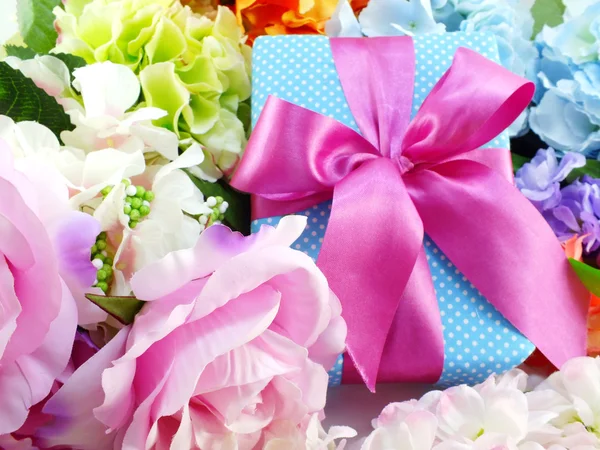 Geschenk-Box mit rosa Schleife und schönen bunten Blumen Hintergrund — Stockfoto