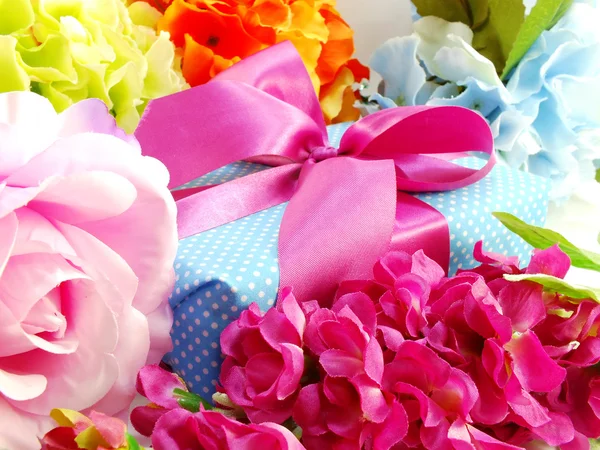 Regalo caja regalo con lazo de cinta rosa y hermoso fondo de flores de colores — Foto de Stock