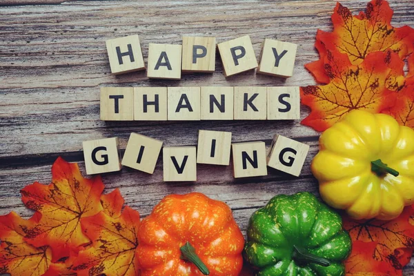 Happy Thanksgiving alphabet letter with pumpkins and autumn leaves on wooden background