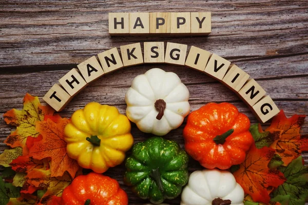 Happy Thanksgiving alphabet letter with pumpkins and autumn leaves on wooden background