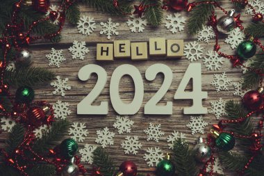 Merhaba 2024 alfabe harfleri ve ahşap arka planda Noel süslemeleri.