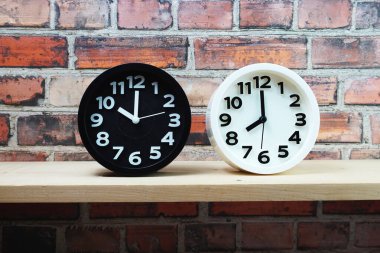 Ahşap raflarda ve tuğla duvar arka planında farklı ülkelerin zaman dilimine sahip saatler