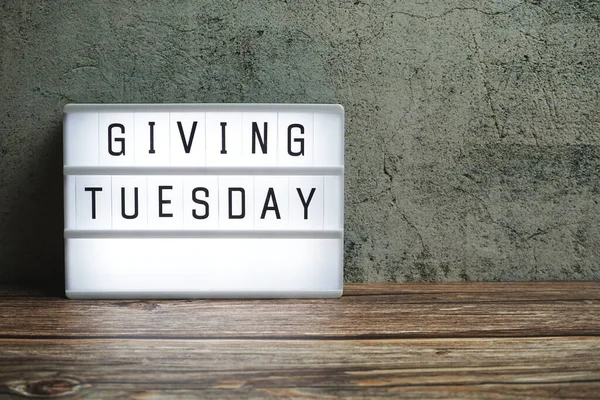 Giving Tuesday word in light box on wooden background