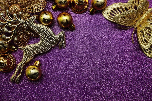 紫色光泽背景下的金色圣诞球和带有空间复制品的金麋鹿圣诞饰物 — 图库照片