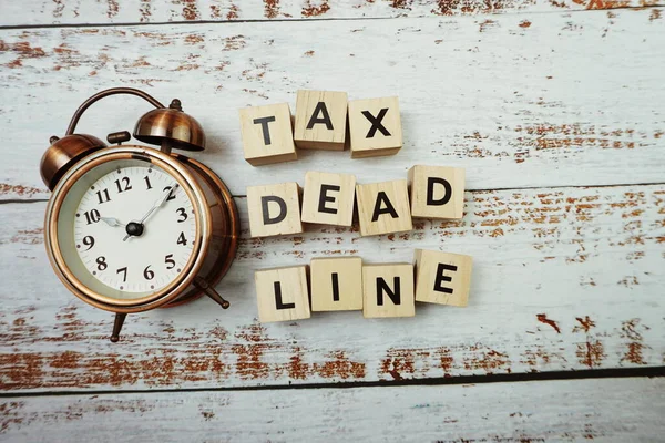 Tax Deadline with alarm clock with space copy on wooden background