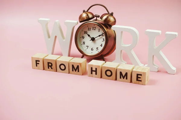 ピンクの背景に目覚まし時計とホームアルファベットの文字から仕事 — ストック写真