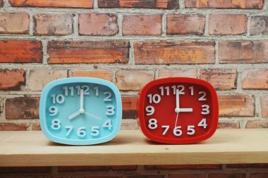 Ahşap raflarda ve tuğla duvar arka planında farklı ülkelerin zaman dilimine sahip saatler