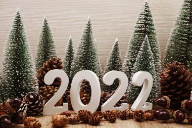 Yeni yılınız kutlu olsun. Yeni yıl arkaplanı, Noel ağacı ve ahşap arka planda çam kozalağı süslemesi.