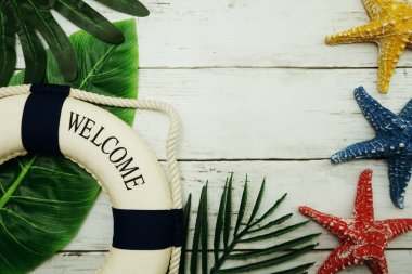 Yeşil izinli yaz konsepti, deniz yıldızı ve ahşap arka planda can simidi dekorasyonu.