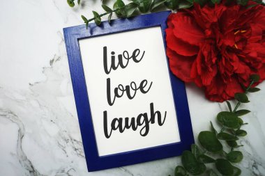 Canlı Aşk Gülüşü mavi çerçevede yeşil izinle ve kırmızı çiçekle mermer arka planda yatıyordu.