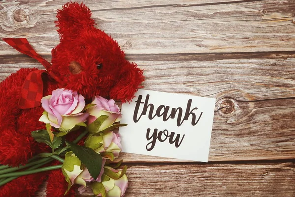 Thank you card with teddy bear and flower decoration on wooden background