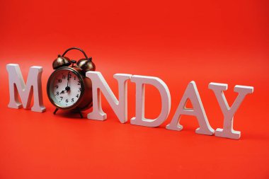 Kırmızı zemin üzerinde alarm saati olan Pazartesi alfabesi harfi