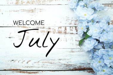 Hoş geldiniz Temmuz metni ve ahşap arka planda mavi çiçek süslemesi