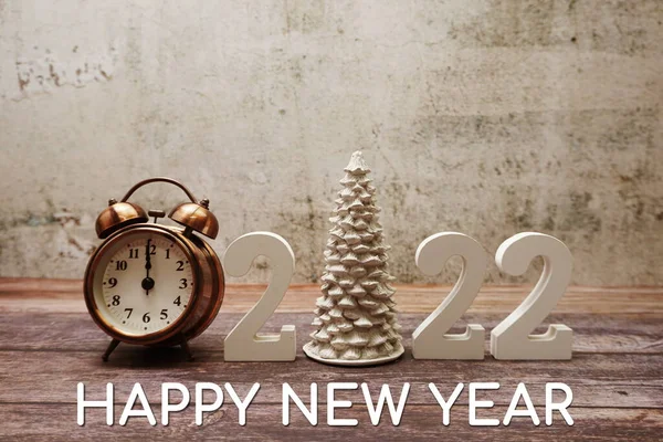 Happy New Year 2022 Calligraphy alphabet letter and Vintage alarm clock with space copy on wooden background
