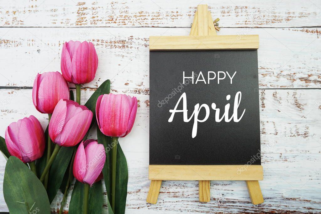 Welcom April text and pink tulip flower decoration on wooden background