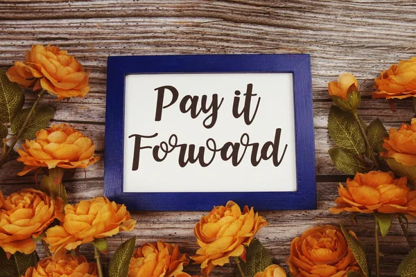 Pay it forward typography text with flower decoation on wooden background