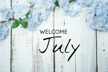 Hoş geldiniz Haziran metni ve ahşap arka planda mavi çiçek süslemesi