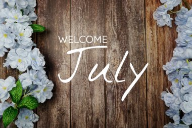 Hoş geldiniz Temmuz metni ve ahşap arka planda mavi çiçek süslemesi