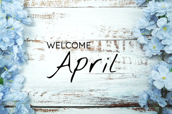 ようこそ4月のテキストと木製の背景に青い花の装飾 — ストック写真