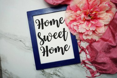 Home Sweet Home hattatlık ve pembe çiçek düz mermer zemin üzerinde yatıyordu