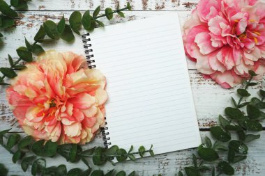 Alarmlı saati ve tahta arka planı olan boş sayfaları olan bir defter.